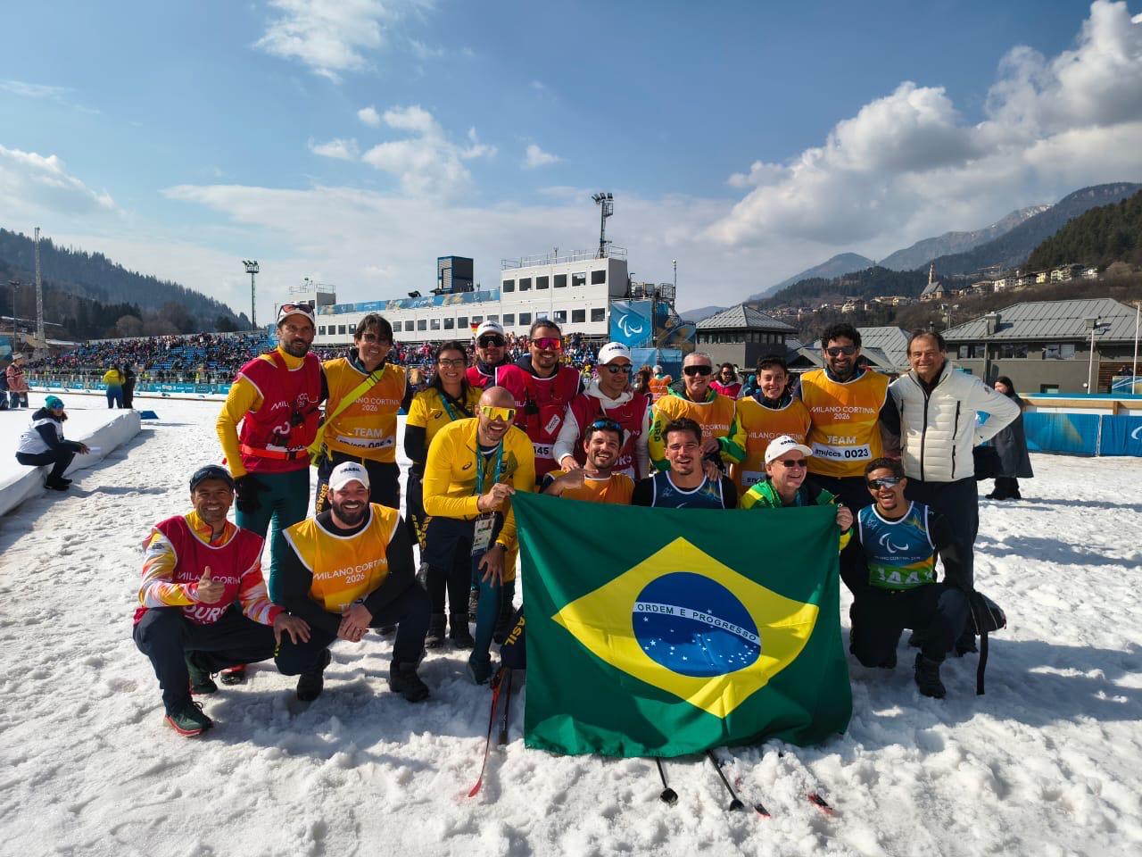 Seleção Brasileira Paralímpica reunida na neve com a bandeira do Brasil